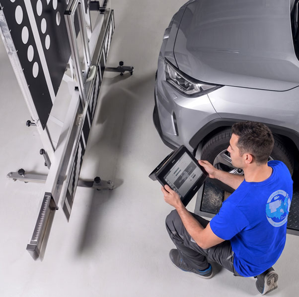 Technician setting up an ADAS calibration target frame beside a vehicle in Mcallen