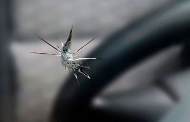 Star break crack radiating across a car windshield near the steering wheel
